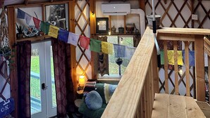 A yurt with a wooden interior, a central pole, and a small window. - Boho Yurt Stay ~ Cozy & Unique ~ Massage Chair (Athens)