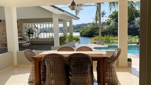 A spacious dining area with a view of a pool and greenery.