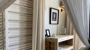 A bedroom with a wooden bed, a bedside table with a picture frame, and a wall-mounted light fixture.