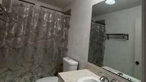 Un baño con inodoro, lavabo y cortina de ducha estampada.