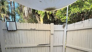 Un patio empedrado con cerca blanca y un dosel blanco.
