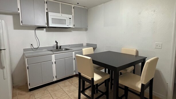 Una cocina compacta con mesa y sillas, ventilador de techo y microondas.