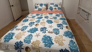 Un dormitorio con cama, cabecera blanca y ventana con persianas.