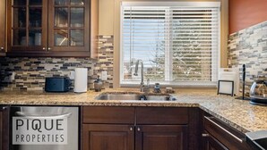 A kitchen with dark wooden cabinets, a tiled backsplash, and a window with blinds. - Urban Oasis - Heated Pool/Hot Tub - Steam Shower - Pets (Edmonton)