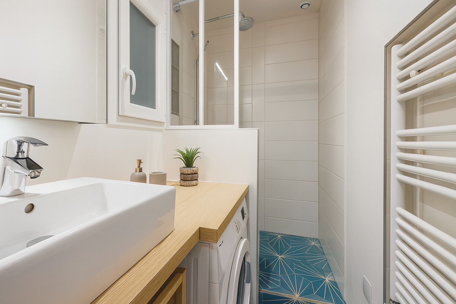 A modern bathroom with a white sink, a mirror, a shower, and a blue tiled floor.