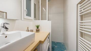 A modern bathroom with a white sink, a mirror, a shower, and a blue tiled floor.