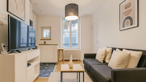 A modern living room with a grey sofa, a coffee table, a TV, and a patterned rug. - Charmant 1 Chambre à Grenelle (Paris)