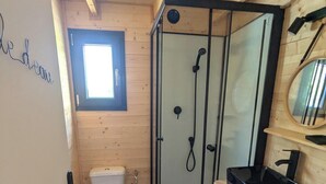 Une petite salle de bain en bois comprenant des toilettes, une douche à parois de verre et un lavabo.