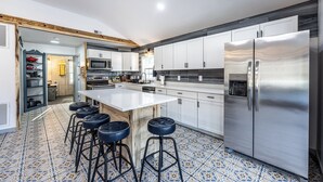 Een moderne keuken met witte kasten, een roestvrijstalen koelkast en een vloer met een patroon van tegels.