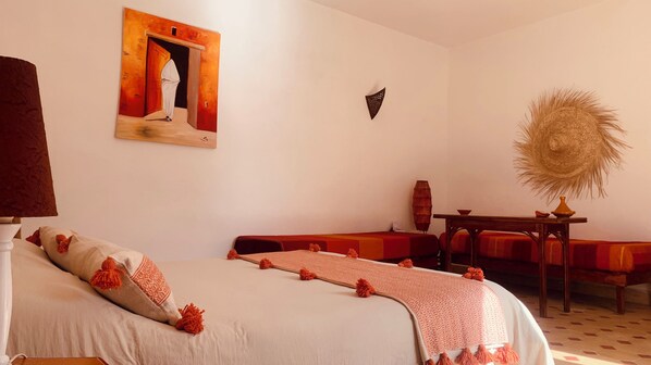 A room with a bed, a sofa, a table, and a wall-mounted artwork.