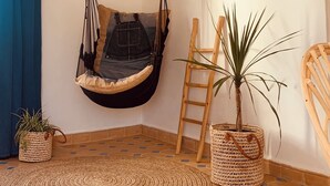 Una habitación con una silla colgante, una escalera y plantas en macetas.