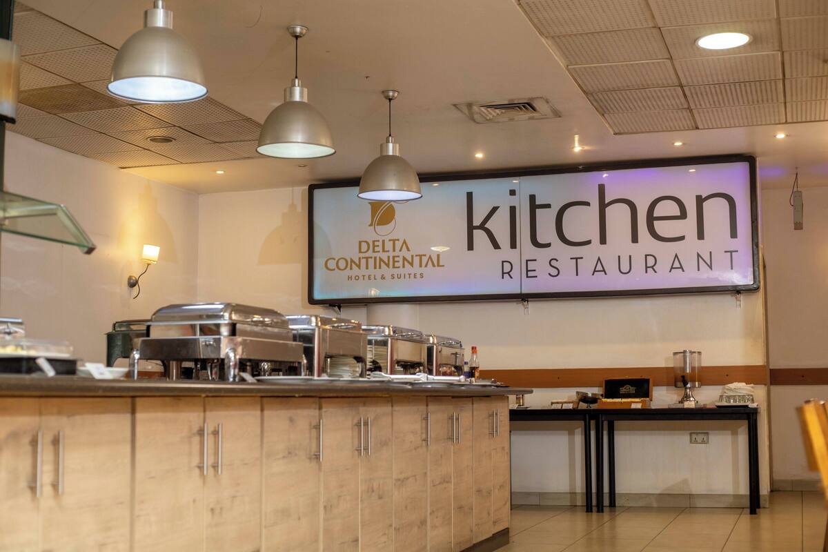 A buffet area with a sign for 'Delta Continental Hotel & Suites Kitchen Restaurant'.