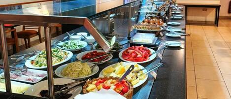 Montaje tipo bufé en un restaurante de hotel, con diversos alimentos y utensilios.