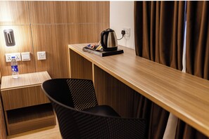 A wooden desk with a kettle, a bottle of water, and a chair. - DELTA CONTINENTAL HOTEL AND SUITE LAGOS (Lagos)