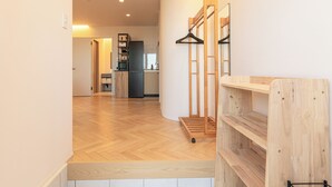 Un salón moderno y abierto con una cocina al fondo, suelo de madera y estanterías empotradas.