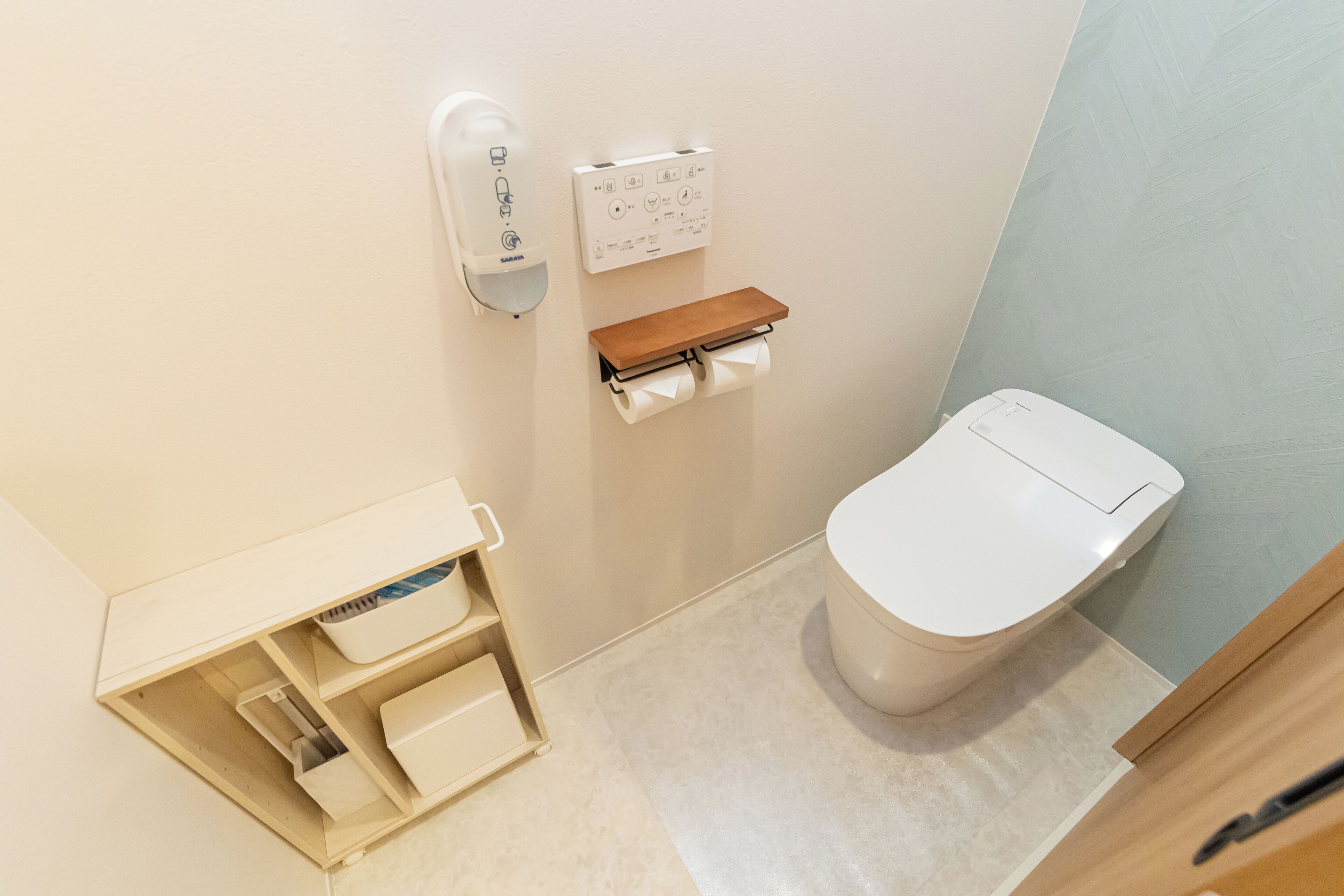 A small bathroom with a toilet, a hand dryer, a soap dispenser, and a towel rack.