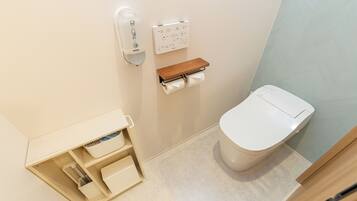 A small bathroom with a toilet, a hand dryer, a soap dispenser, and a towel rack.
