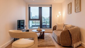Een moderne woonkamer met een bank, fauteuil en een bijzettafeltje met een decoratief object.