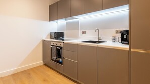 Een moderne keuken met een ingebouwde oven, magnetron en koffiezetapparaat, met een minimalistisch ontwerp en een neutrale kleurenpalet.