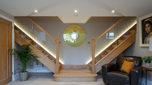 Un intérieur moderne avec un escalier, un fauteuil en cuir et une plante en pot.