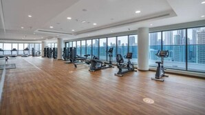 Un'ampia palestra con diverse attrezzature per l'allenamento e grandi finestre che offrono vista sulla città.