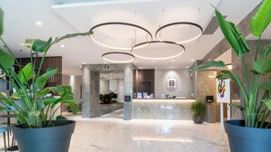 A hotel reception area with a marble floor, a reception desk, and a logo on the wall.