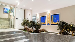 Un vestíbulo de hotel moderno con escalones de mármol, plantas decorativas y arte abstracto en las paredes.