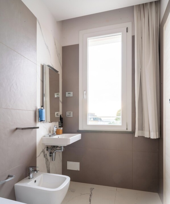 Een moderne badkamer met een bad, een wastafel en een raam.