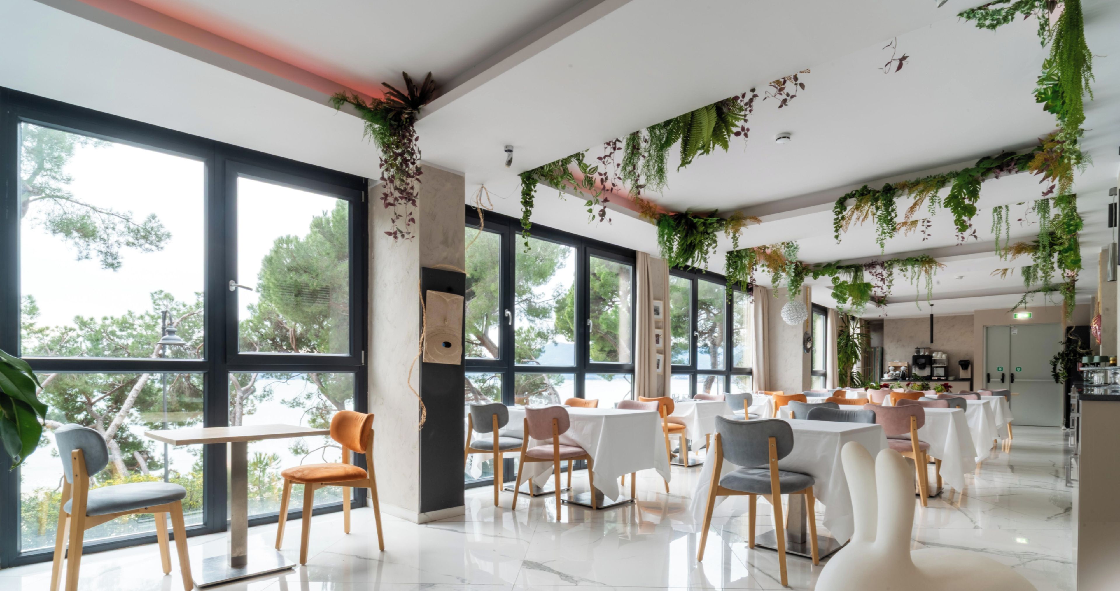 Ein modernes Restaurant mit großen Fenstern, Holzstühlen und -tischen.