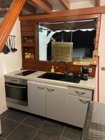 A compact kitchen with a sink, stove, and cabinets.