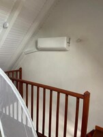 A staircase with wooden railings and an air conditioning unit mounted on the wall above.
