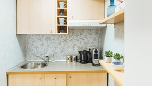 Een kleine keuken met een spoelbak, houten kastjes, een koffiezetapparaat en een waterkoker.