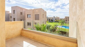 A balcony with a view of a swimming pool and surrounding buildings. - Cozy apartment with pool in Argan, 3 bedrooms (Marrakesh)