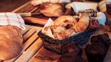 A variety of breads and pastries on a wooden table.