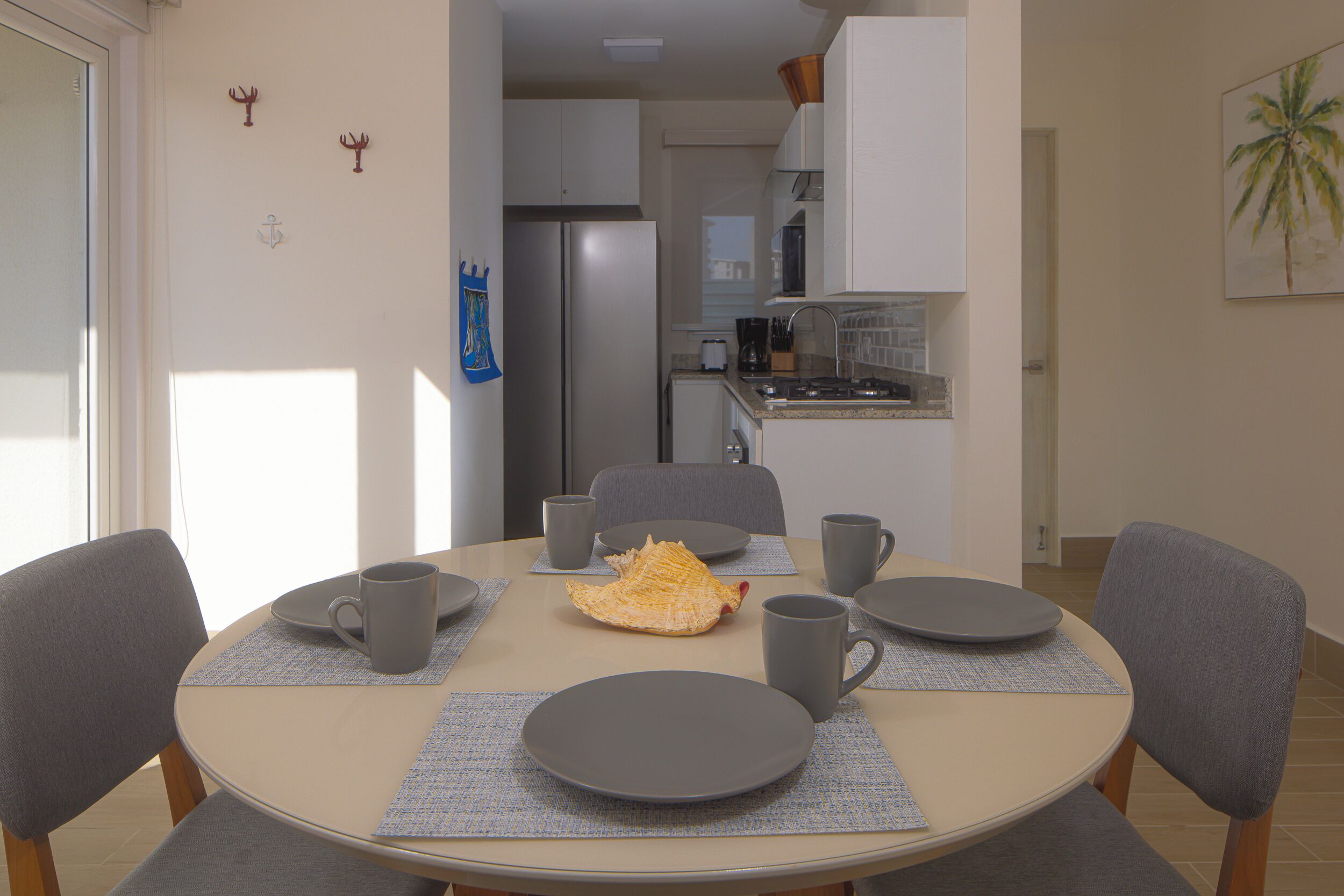 A dining area with a round table, six chairs, and a kitchen in the background.