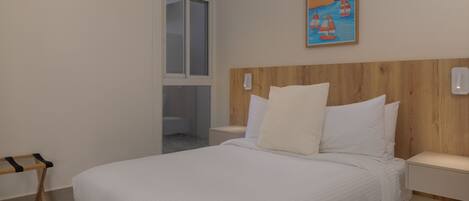 A bedroom with a large bed, a wooden headboard, a nightstand, a window with a view, and a painting on the wall.