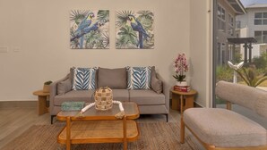 Un salón con un sofá, una mesa de centro y dos cuadros de loros colgados en la pared.