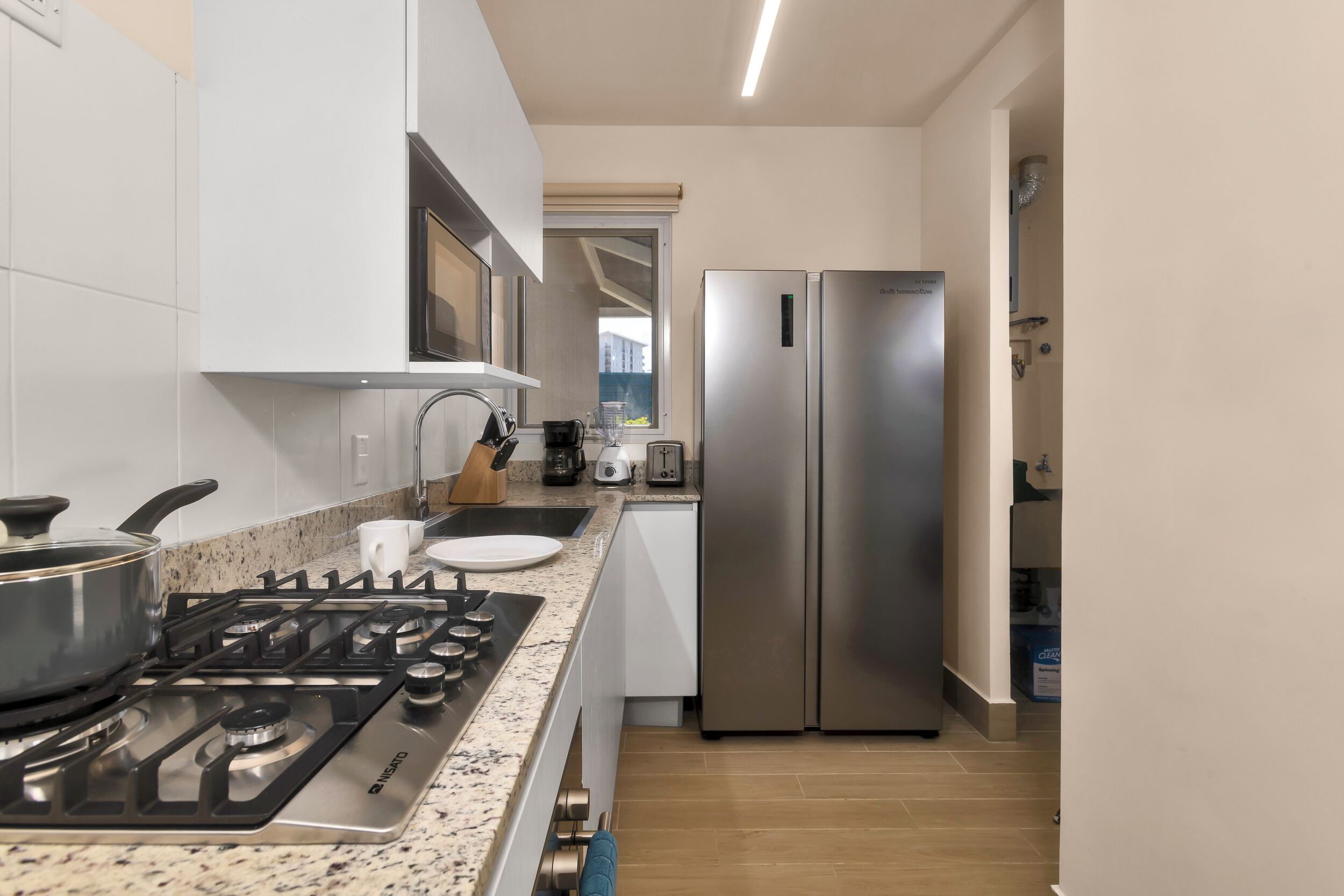 A modern kitchen with a gas stove, stainless steel refrigerator, and white cabinets.