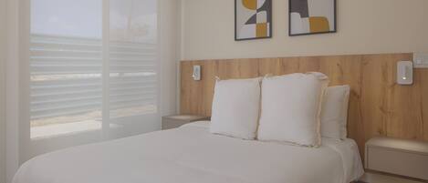 Quarto com uma cama grande, cabeceira de madeira, duas mesas de cabeceira e uma janela com persianas.