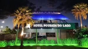 Un hotel con un letrero que dice "HOTEL POUSADA DO LAGO" de noche, con techo azul y entorno iluminado.