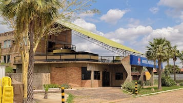 Un hotel con un paseo techado, palmeras y fachada de ladrillo.