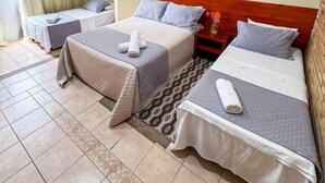 Habitación de hotel con dos camas, una mesita, una silla y un equipo de aire acondicionado.