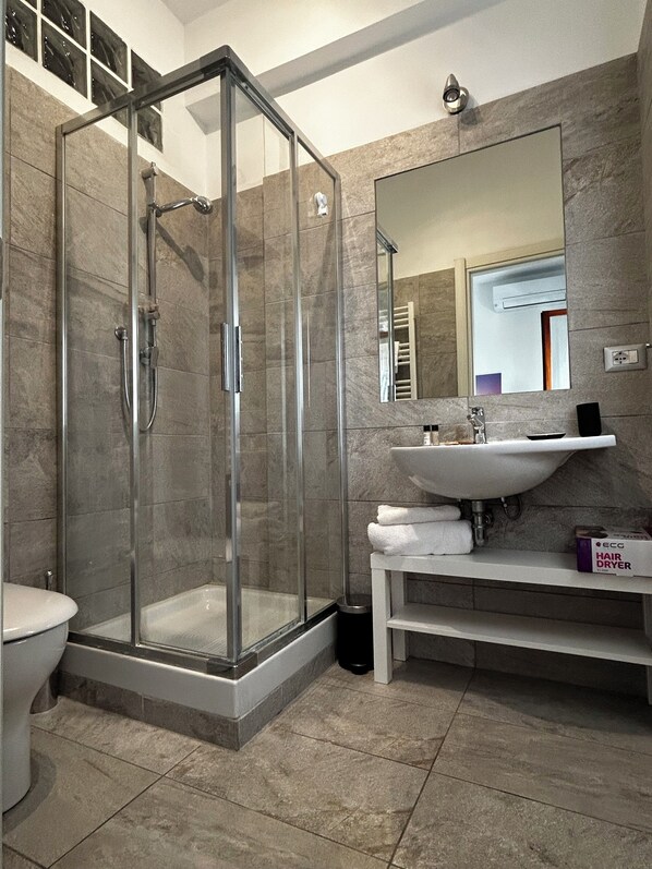 A modern bathroom with a glass-enclosed shower, a sink with a mirror, and a toilet. - 5 minutes from St. Peter's Square - spacious and comfortable (Roma)
