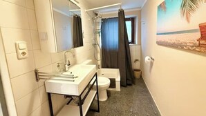 Casa de banho compacta com lavatório branco, sanita e chuveiro.
