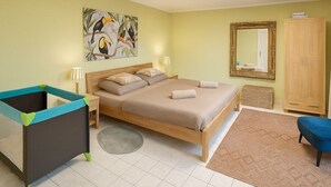 Quarto com cama, mesa de cabeceira, penteadeira, espelho, quadro e um pequeno cercadinho.