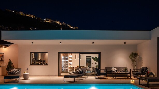 A modern poolside area with a clear view of the pool, a seating area with sofas and chairs, and a large window overlooking the pool. - NEW! Villa Bella Ciao: A Stylish 3-Bedroom Retreat with Spectacular Split and Sea Views (Klis)