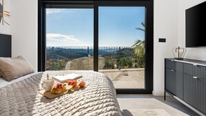 A bedroom with a large bed, a view of a hilly landscape through a sliding door, and a modern TV on the wall. - NEW! Villa Bella Ciao: A Stylish 3-Bedroom Retreat with Spectacular Split and Sea Views (Klis)