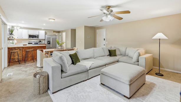 A modern living room with a sectional sofa, ottoman, and a floor lamp.