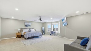 A bedroom with a bed, bedside table, lamp, and a large window.