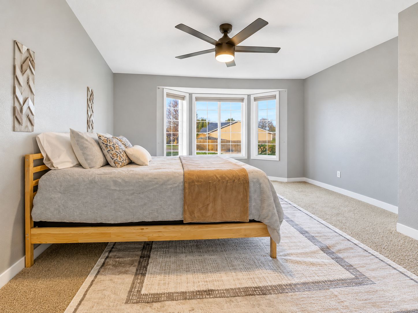 A bedroom with a bed, a ceiling fan, and a view through a window.